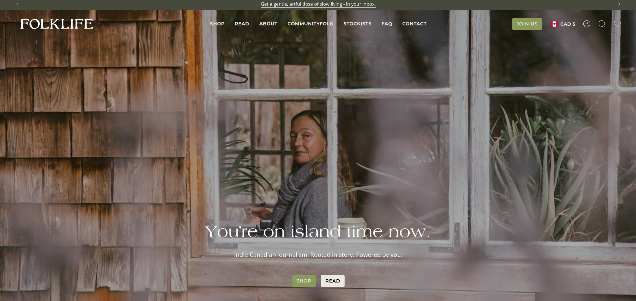 Woman looking out a window with a blurred effect, wooden wall and plant in the background.